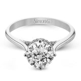 This elegant white gold engagement ring takes a round center and is adorned with a delicate under halo, and a line of diamonds on the side profile 0.13 ctw