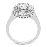 Crafted in 18K white gold, this distinctive ring is an ode to Art Deco design & features a halo of RD diamonds 0.23 ctw, surrounded by a burst of baguette shaped diamonds 0.70 ctw.