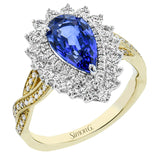 A unique color ring in 18K 2tone features a pear shaped sapphire center 2.56 ctw., surrounded by a double halo of white diamonds .76 ctw, and has a diamond accented yellow gold twist shank.