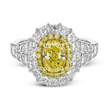 This very special ring is custom crafted for a 1.34 ct oval yellow diamond at the center. This stone is then surrounded by an inner halo of round yellow diamonds and a larger outer halo of princess cut white diamonds.