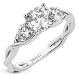 This 18K three stone ring in two-tone gold has a delicate twist design with a polished yellow gold side and a polished white gold side. The center is highlighted by two RD diamonds.