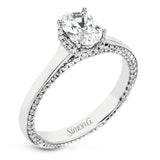 This engagement ring is made from an oval center stone and features a low halo as well as diamonds extended down the sides of the ring.