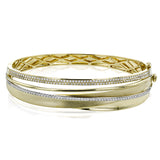 This 18k yellow gold bangle showcases a sophisticated matte surface effect on the gold, accented by several lines of .96 ctw of white diamonds.