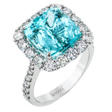 This stunning right-hand ring features a cushion cut 6.02 ct. paraiba tourmaline, surrounded by a halo of white diamonds with diamonds half way down the sides 1.47 ctw.