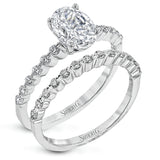 This contemporary wedding set features .48 ctw of diamond side stones and is designed to perfectly showcase an oval center stone.
