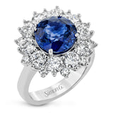This bold cocktail ring features a central 4.75 ct blue sapphire surrounded by 2.91 ctw of white diamonds placed in geometric halo.