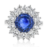 This bold cocktail ring features a central 4.75 ct blue sapphire surrounded by 2.91 ctw of white diamonds placed in geometric halo.