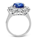 This bold cocktail ring features a central 4.75 ct blue sapphire surrounded by 2.91 ctw of white diamonds placed in geometric halo.