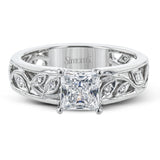 A delicate floral design highlights this vintage style engagement ring accented by .09 ctw of shimmering round cut white diamonds.