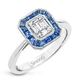 This white gold ring recalls the charm of a past era with a halo of custom-fitting sapphires surrounding a mosaic of .18 ctw diamonds.