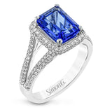 This splendid white gold ring features a delicate split shank and halo, set with .46 ctw of round white diamonds, framing a lovely 2.71 ctw emerald cut tanzanite.