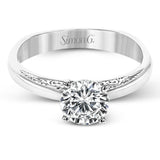 Beautiful in its simplicity, this sleek white gold ring accentuates its centerpiece with delicate engraved details on either side.