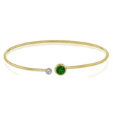 This understated yellow gold bangle features a subtle .08 ctw white diamond accent opposite a stunning .65 ctw emerald. Perfect for stacking.