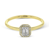 This exquisite, minimalist yellow gold ring features a halo containing .04 ctw of round white diamonds encircling a .16 ctw emerald cut white diamond