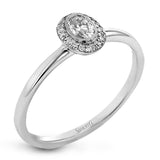 This exquisite, minimalist white gold ring features a halo containing .05 ctw of round white diamonds encircling a .17 ctw oval shaped white diamond
