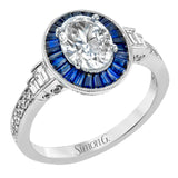 This remarkable ring features milgrain edging and .75 ctw of baguette shaped sapphires in its halo, flanked by .11 ctw of round white diamonds and .16 ctw of baguette shaped white diamonds.