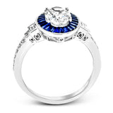 This remarkable ring features milgrain edging and .75 ctw of baguette shaped sapphires in its halo, flanked by .11 ctw of round white diamonds and .16 ctw of baguette shaped white diamonds.
