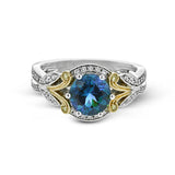 This two-toned vintage inspired right hand ring features a blue zircon center 3.11 ctw. surrounded by white diamonds 0.25 ctw and accented by natural yellow diamonds set in a yellow gold filigree detail.