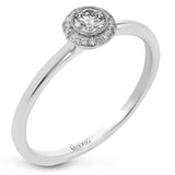 This exquisite, minimalist yellow gold ring features a halo containing .04 ctw of round white diamonds encircling a .16 ctw round white diamond centerpiece