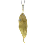 This pendant appears like a realistic leaf cast in gold that sparkles with two dew drops of bezel set diamonds totaling .08 ctw.
