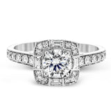 This sleek, contemporary white gold engagement ring contains .35 ctw of round white diamonds and .19 ctw of baguette shaped diamonds on its shank and unique, geometric halo