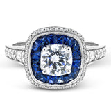 Specially shaped sapphires formed a halo around the center stone in this remarkable engagement ring, accented by .42 ctw of white diamonds as well.