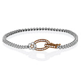 This two tone 18k white and rose gold buckle bracelet contains .98 ctw of white round brilliant diamonds, a .02 ct pink diamond, and a tiny flower design.