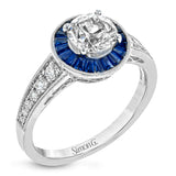 This 18k white gold engagement ring add something special with .56 ctw of baguette sapphires in a halo around the center stone. A total of .36 ctw of white diamonds finish this remarkable design.