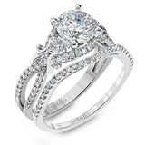 Featuring a delicately twisted shank, this brilliant white gold engagement ring and complimentary wedding band are set with .55 ctw of round cut white diamonds.