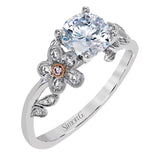 Featuring delicate floral designs on the shank, this modern white gold ring is complemented by .19 ctw of round cut white diamonds and .02 ctw pink diamond accents.