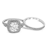 This remarkable white gold engagement ring and wedding band set features a contemporary setting with an eye-catching halo highlighted by .67 ctw of round cut white diamonds.