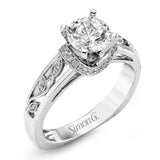 Set with delicate floral patterns, this classic white gold engagement ring is highlighted with .12 ctw round cut white diamonds.