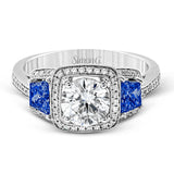 Featuring an elegant classic design, this white gold engagement ring is set with .23 ctw round cut white diamonds and side accents of .62 ctw trapezoid cut sapphires.