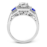 Featuring an elegant classic design, this white gold engagement ring is set with .23 ctw round cut white diamonds and side accents of .62 ctw trapezoid cut sapphires.