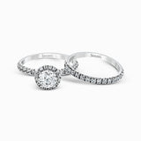 The classic halo design of this white gold engagement ring and wedding band are elevated by .80 ctw of shimmering round cut white diamonds.