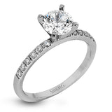 Featuring a modern take on a classic design, this white gold engagement ring and wedding band are inset with .58 ctw of glimmering round cut white diamonds.