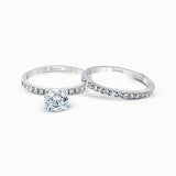 Featuring a modern take on a classic design, this white gold engagement ring and wedding band are inset with .58 ctw of glimmering round cut white diamonds.
