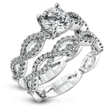 The intricate twisted design of this modern white gold engagement ring and wedding band set is set with .65 ctw of striking round cut white diamonds.