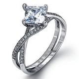 This dramatic white gold engagement ring and wedding band set are highlighted by .23 ctw of dazzling round cut white diamonds in a distinctive modern twist design.