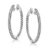 Featuring a classic hoop style, these white gold earrings are accented with .85 ctw of gleaming round cut white diamonds.