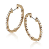 Featuring a classic hoop style, these white gold earrings are accented with .85 ctw of gleaming round cut white diamonds.