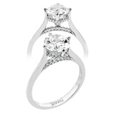This elegant white gold engagement ring takes a round center and is adorned with a delicate under halo, and a line of diamonds on the side profile 0.13 ctw