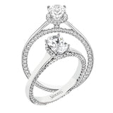 This engagement ring is made from an oval center stone and features a low halo as well as diamonds extended down the sides of the ring.