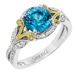 This two-toned vintage inspired right hand ring features a blue zircon center 3.11 ctw. surrounded by white diamonds 0.25 ctw and accented by natural yellow diamonds set in a yellow gold filigree detail.
