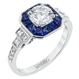 This 18k white gold engagement setting would be a perfect 'something blue' with .79 ctw of baguette sapphires in a halo surrounding the center stone. These are framed by .33 ctw of princess cut diamonds and .11 ctw of round brilliant diamonds.