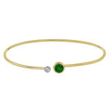 This understated yellow gold bangle features a subtle .08 ctw white diamond accent opposite a stunning .65 ctw emerald. Perfect for stacking.
