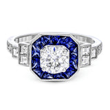 This 18k white gold engagement setting would be a perfect 'something blue' with .79 ctw of baguette sapphires in a halo surrounding the center stone. These are framed by .33 ctw of princess cut diamonds and .11 ctw of round brilliant diamonds.